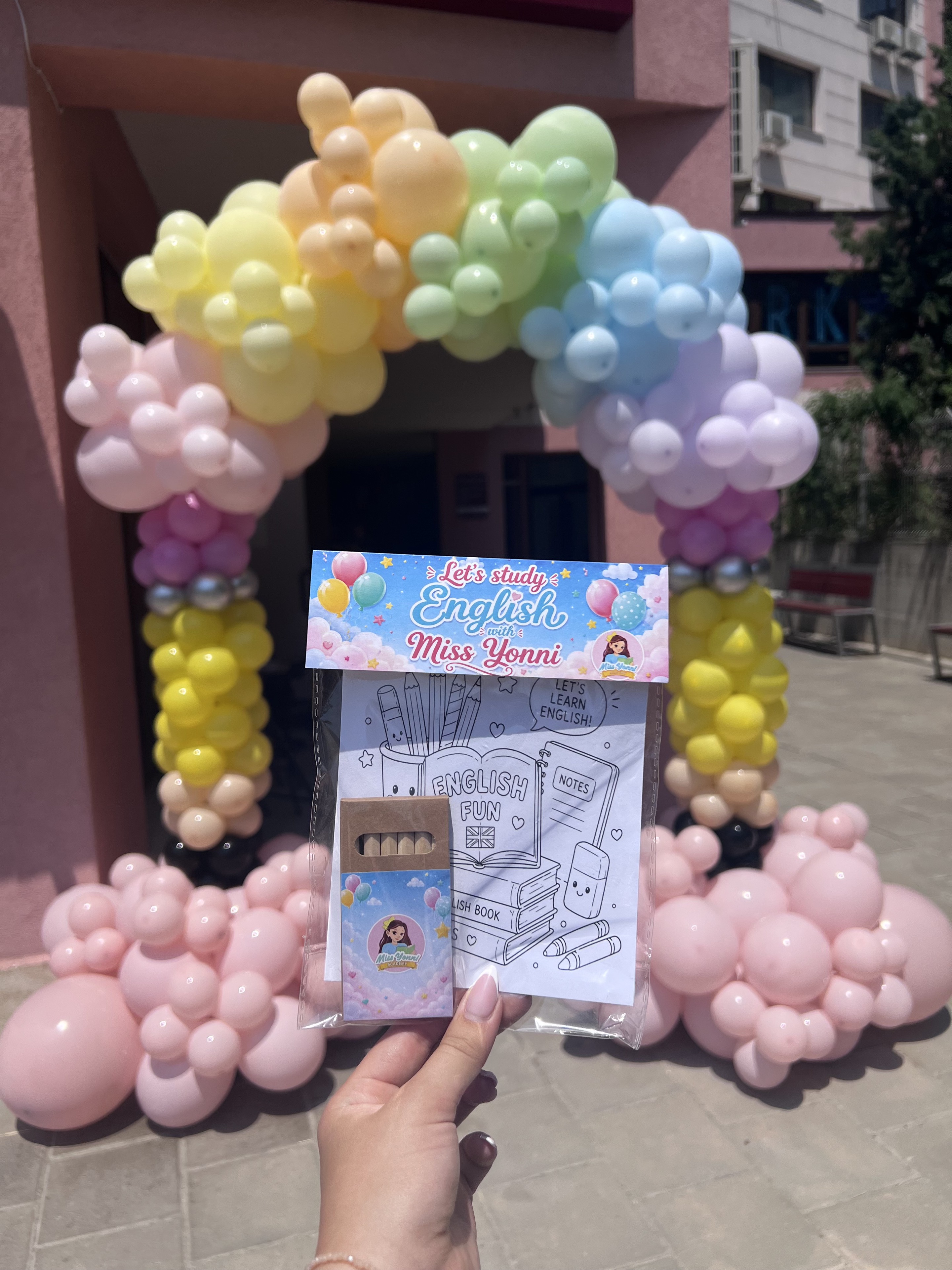 Pastel balloon arch with personalized English academy activity pack in front