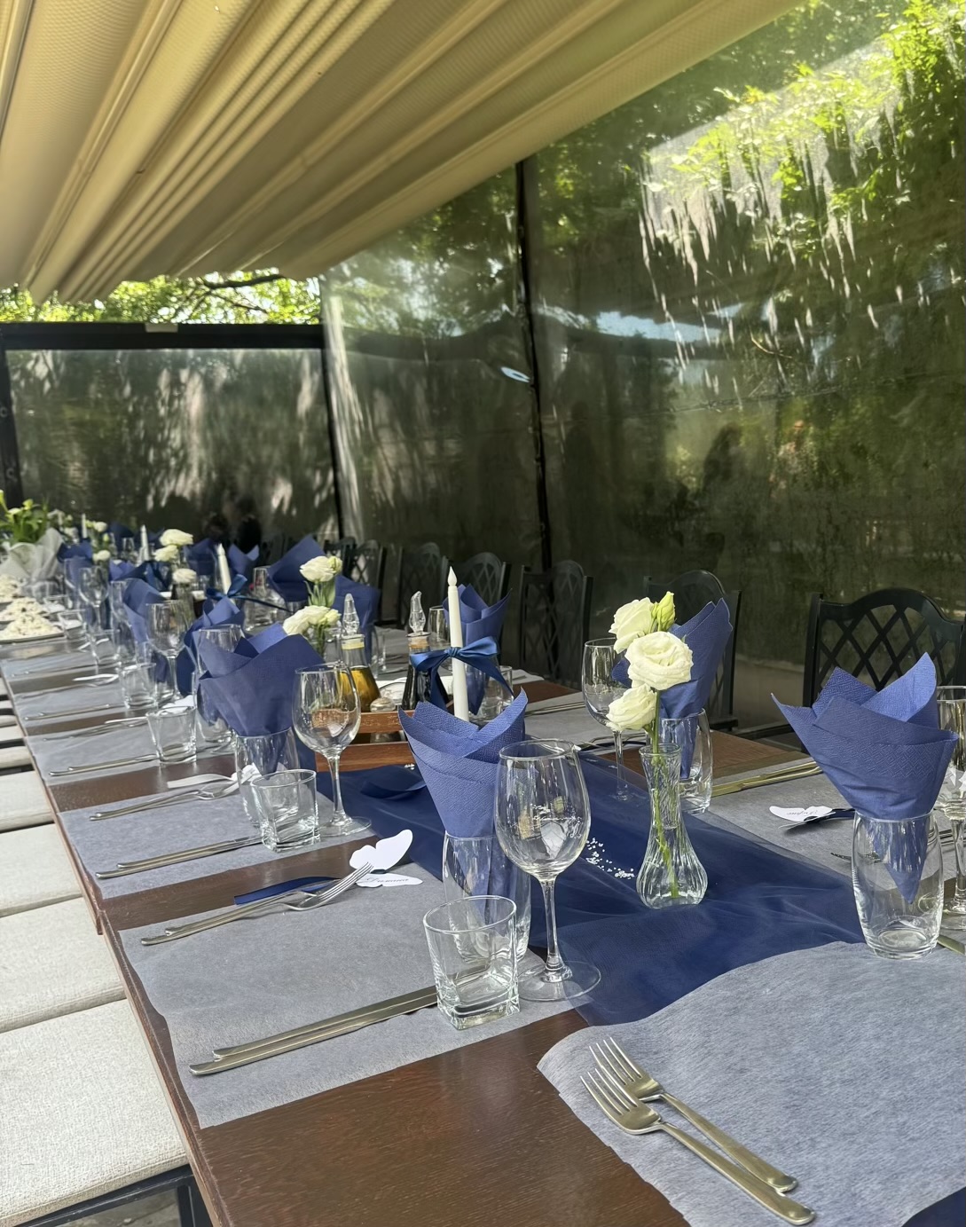 Navy and grey table setting with white roses, glassware, and ribbon details