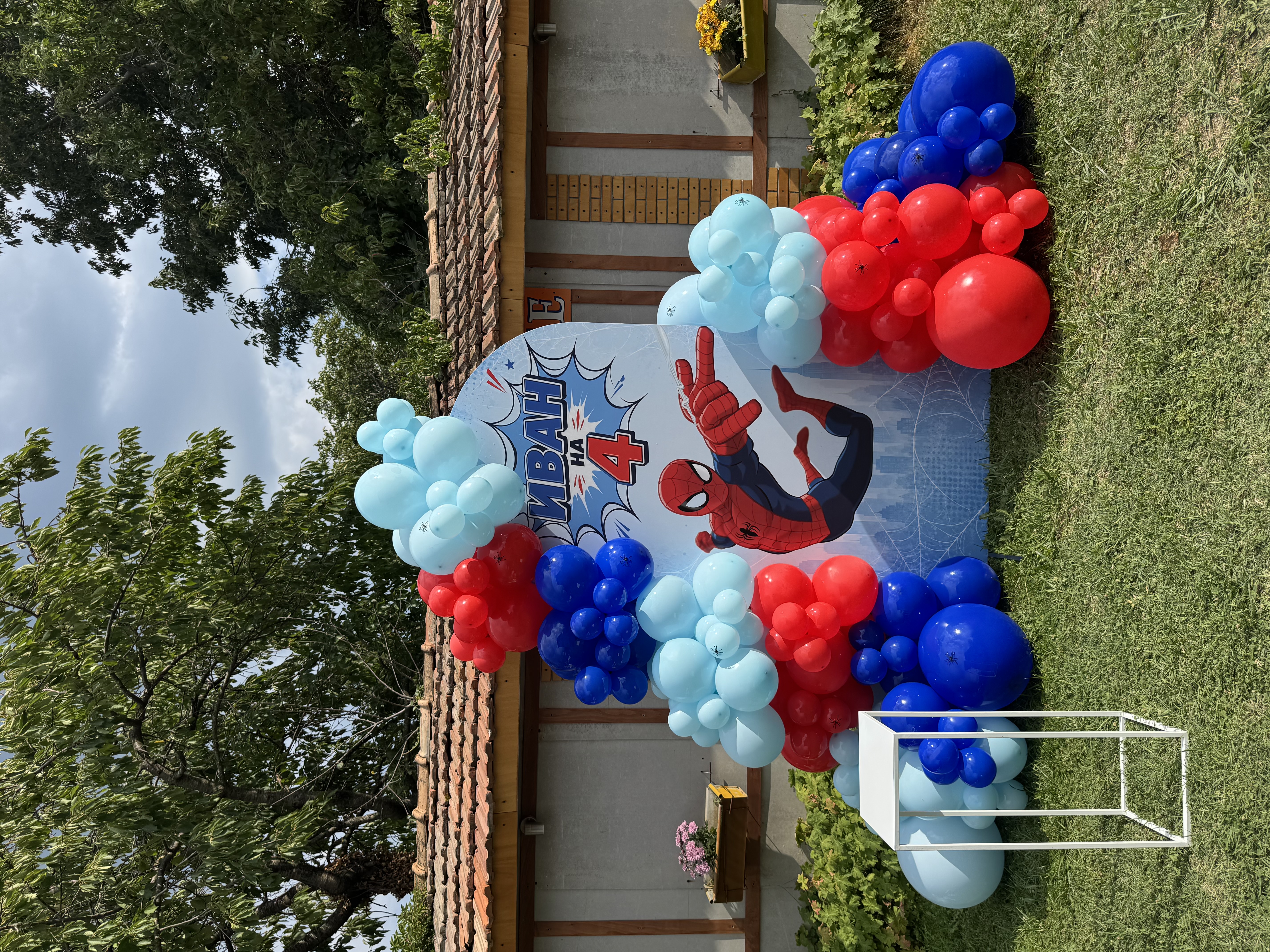 Spider-Man themed fourth birthday decor with red, blue, and light blue balloon clusters